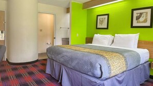 Quarto de hotel com uma cama, uma porta e uma parede com duas molduras.