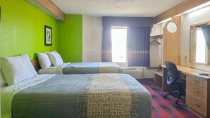 Habitación de hotel con dos camas, un escritorio, una silla, un espejo y una ventana con cortinas.