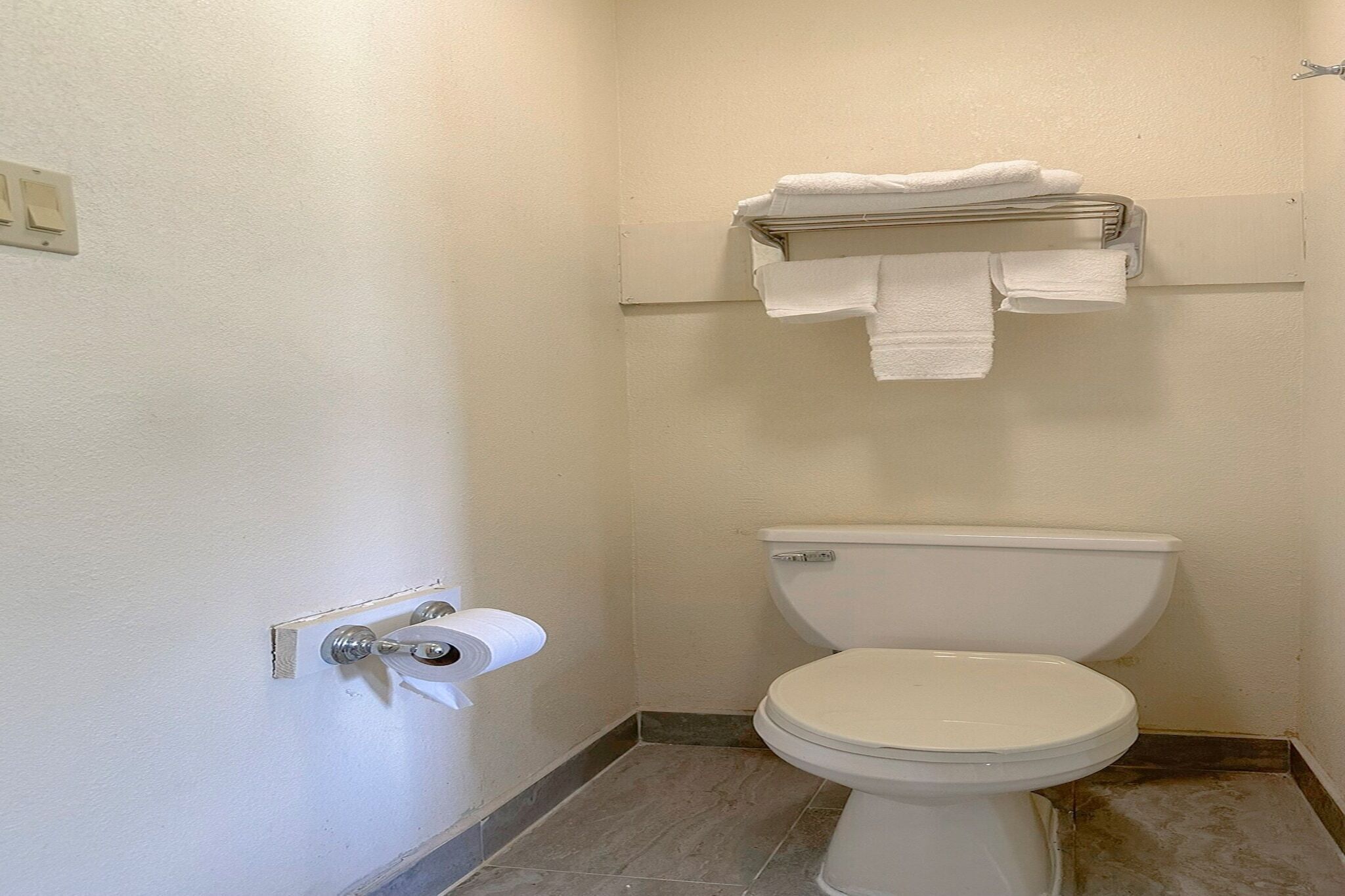 A small, clean bathroom with a toilet, a towel rack, and a paper towel dispenser.
