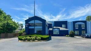 Een modern gebouw met een ruime garage-ingang, heldere lucht en een verzorgd gazon.
