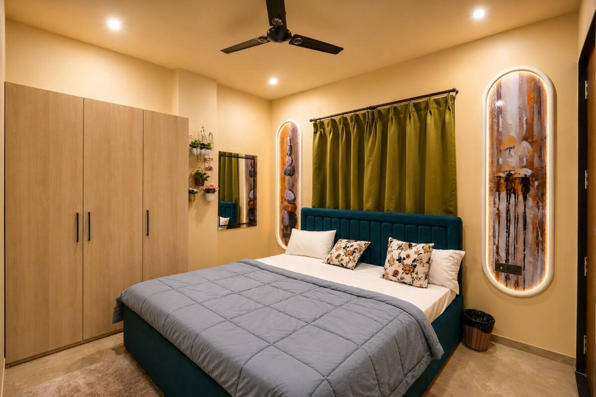 Un dormitorio con cama, ventilador de techo, armario, cortina verde y decoración en la pared.