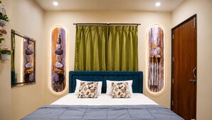 Ein Schlafzimmer mit einem Bett, zwei Kissen, einem Kopfteil, einem grünen Vorhang und einer Holztür.