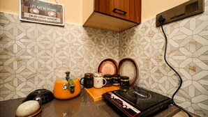 Eine Küche mit einer Kaffeemaschine, einem Wasserkocher und Gläsern auf der Arbeitsplatte, einem Schild an der Wand und einem Holzschrank.