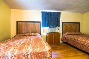Habitació amb dos llits, amb capçaleres de fusta, un petit armari de fusta i una finestra amb cortines.