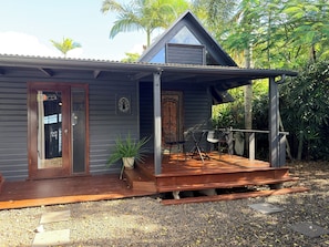 A wooden house with a porch, a door, and a small window.