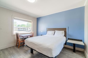 A bedroom with a bed, a desk, and a chair.