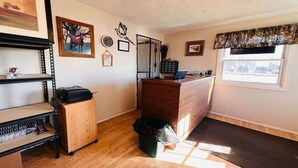 Une pièce avec un bureau en bois, un ordinateur, une poubelle et une fenêtre donnant sur un paysage agréable.
