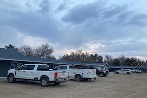 Un estacionamiento con varias camionetas pickup, un edificio de fachada azul y un cielo despejado.