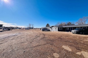 Una zona residencial con casas, un camino de tierra y coches aparcados.