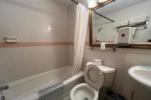 A bathroom with a bathtub, toilet, sink, and a mirror.