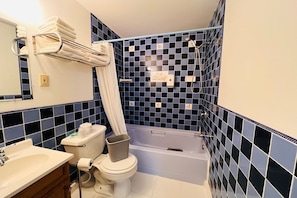 Une salle de bain équipée d’une baignoire, de toilettes, d’un lavabo et d’un porte-serviettes.