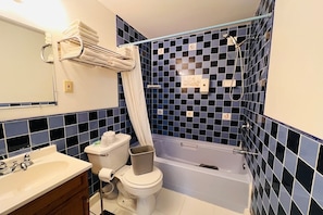 A bathroom with a bathtub, toilet, sink, and a mirror.