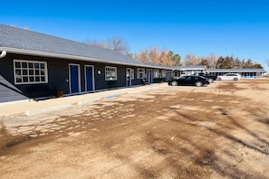 A motel with a single-story structure, a covered parking area, and a clear sky.