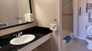 A bathroom with a sink, mirror, towel rack, shower, and toilet.