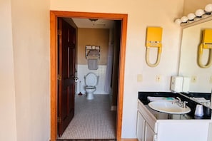 A bathroom with a toilet, sink, and mirror.