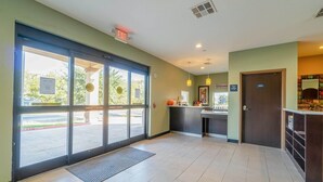 A reception area with a glass door entrance, a reception desk, a 'Welcome' sign, and a 'Parking' sign. - 2 Queen Beds|Non-Smoking (Moulton, TX)