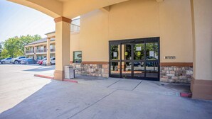 A hotel entrance with a stone facade, a glass door, and a parking lot visible in the background. - 2 Queen Beds|Non-Smoking (Moulton, TX)