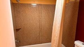 A bathroom with a bathtub, toilet, and shower curtain. - King Bed|Non-Smoking (Newport News PA)
