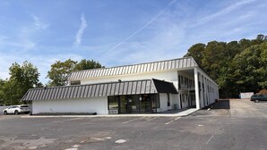 Ein modernes Gebäude mit flachem Dach, großen Fenstern und einem überdachten Eingangsbereich.