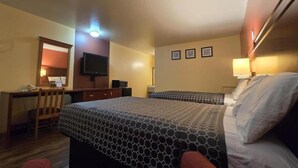 Una camera d'albergo con due letti, una scrivania, una sedia, una televisione e uno specchio.