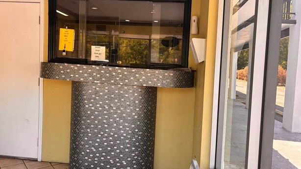 Una reception con una vetrata, un bancone piastrellato e una porta a sinistra.