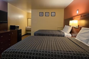 Una camera d'albergo con due letti, una televisione, un comò e un bagno sullo sfondo.