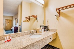 A hotel bathroom with a sink, mirror, towel rack, and a towel dispenser. - King Bed Accessible|Grenada MS (Grenada MS)