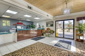 A reception area with a wooden ceiling, a reception desk, a clock, and a large window. - King Bed Accessible|Grenada MS (Grenada MS)