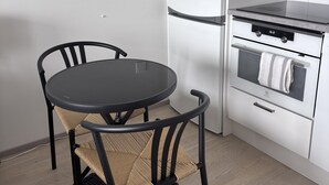 Ett kök med ett runt bord, stolar, ett kylskåp och en ugn.