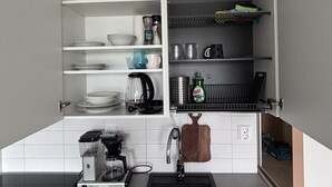 Ett kök med en inbyggd diskmaskin, en kaffebryggare och en träskärbräda som hänger på väggen.