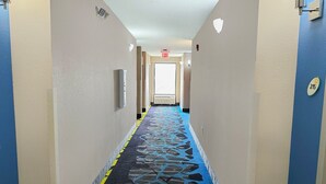 Un pasillo de hotel con alfombra estampada, un letrero de salida y una puerta con el número 215.