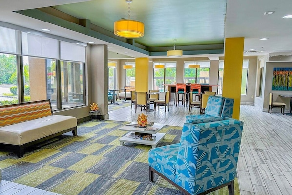 A spacious lobby with a sofa, armchairs, a coffee table, and a dining area with tables and chairs.