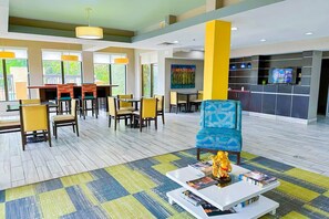 A hotel lobby with a dining area, a TV, and a statue on a coffee table.