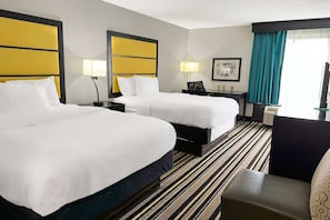 A hotel room with two beds, a striped carpet, a desk with a lamp, and a chair. - 2 Queen Beds Non-Smoking (Jackson)