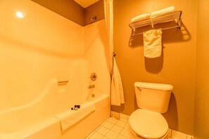 Een badkamer met een bad, toilet en handdoekrek.