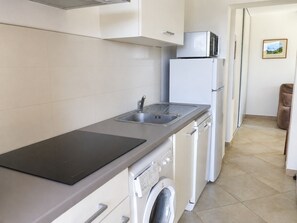 Eine Küche mit Spüle, Mikrowelle, Kühlschrank und Waschmaschine.