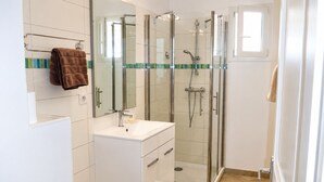 A modern bathroom with a glass-enclosed shower, a white vanity with a mirror, and a towel rack. - LE JASMIN 1-Bedroom Apartment, Sleeps 4 (Serra-di-Ferro)