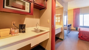 A hotel room with a microwave, coffee maker, sink, and a bed with a red blanket. - 2 Queen Beds Suite Non-Smoking (Jonesboro, AR)