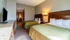 Ein Hotelzimmer mit zwei Betten, einem Fernseher, einem Schreibtisch und einer Lampe.