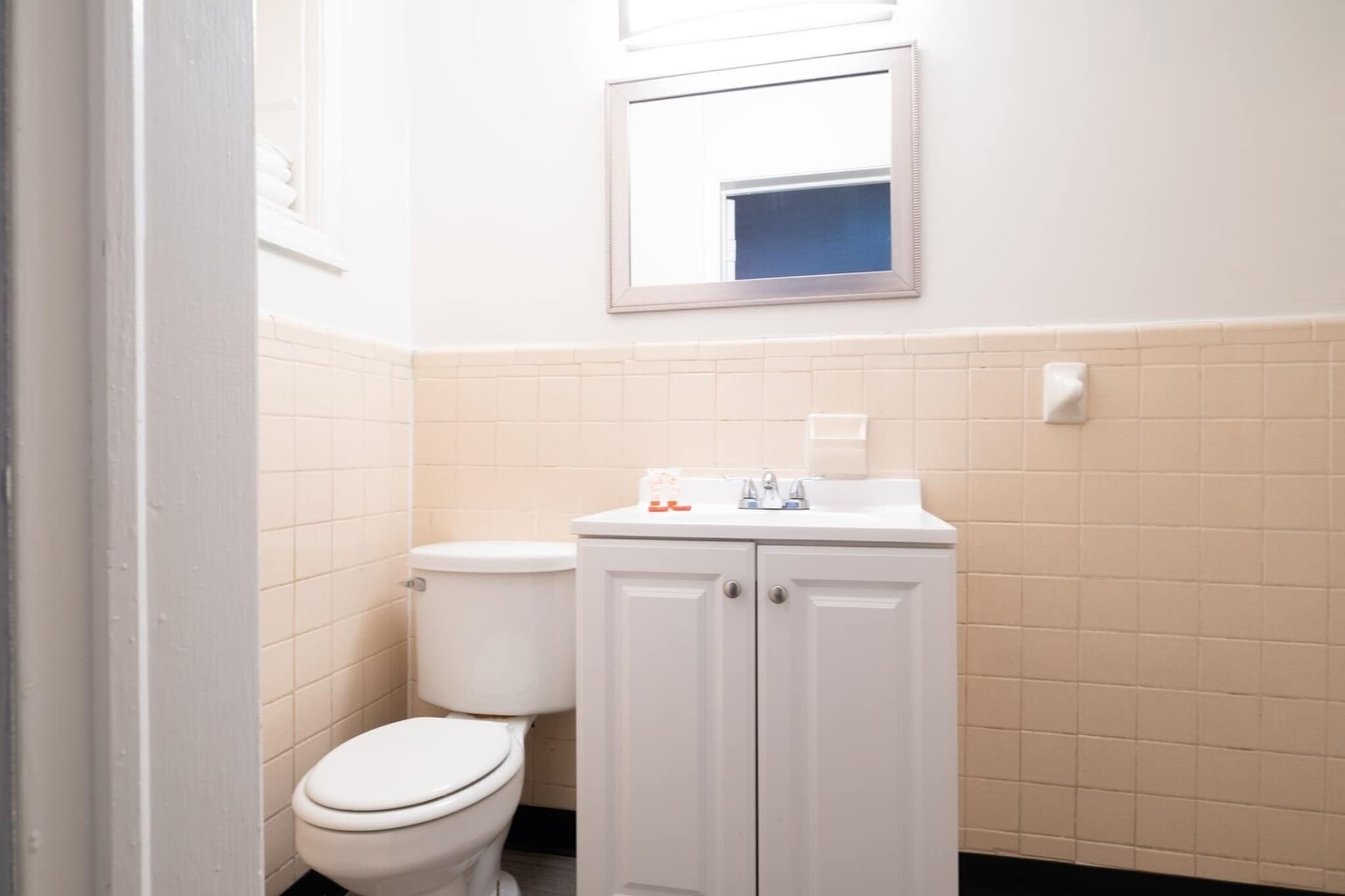 Un baño con inodoro, lavabo, armario y espejo.