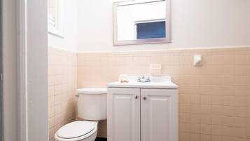 Un baño con inodoro, lavabo, armario y espejo.