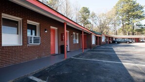 A motel with a brick facade, red accents, and a parking lot. - Jonesboro |2 Queen Bed (Jonesboro)
