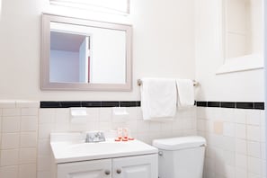 Une salle de bain avec un lavabo blanc, un miroir et des toilettes.