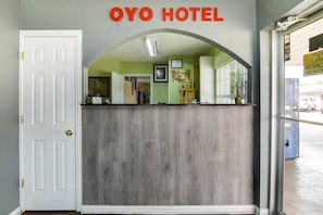 A hotel reception desk with a white door, a sign reading 'OYO HOTEL,' and a 'Deluxe Inn' sign above the counter. - 2 Full Bed|Smoking|Killeen TX (Killeen TX)