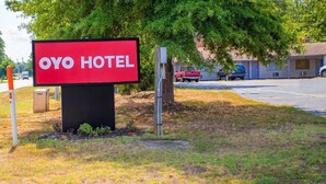 A sign for the Oyo Hotel with a clear view of the surrounding parking area and a building in the background.