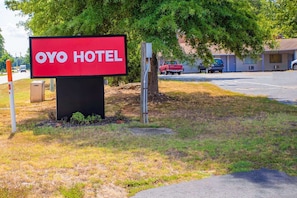 Señal del Hotel Oyo con vista clara del área de estacionamiento y un edificio al fondo.