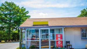 A building with a glass entrance, a yellow sign on the roof, and a red sign advertising extended stay weekly.
