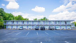 Un motel con aparcamiento, varias habitaciones y una escalera que sube al piso superior.