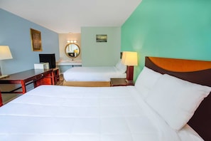 A hotel room with two beds, a desk, a chair, a mirror, and a wall-mounted lamp. - Kernersville NC|2 Full Bed (Kernersville NC)
