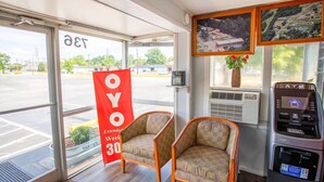 Una habitación con dos sillas, una ventana con vista a un estacionamiento, un cajero automático y un cartel rojo.